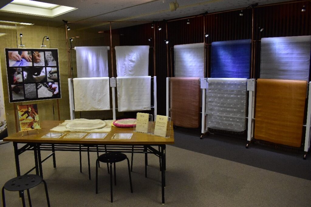 Photograph of the textile hanger racks displaying colorful textiles