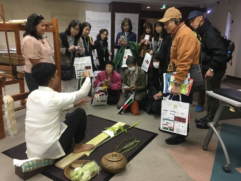 Photograph of visitors watching the weaving and scraping demonstration