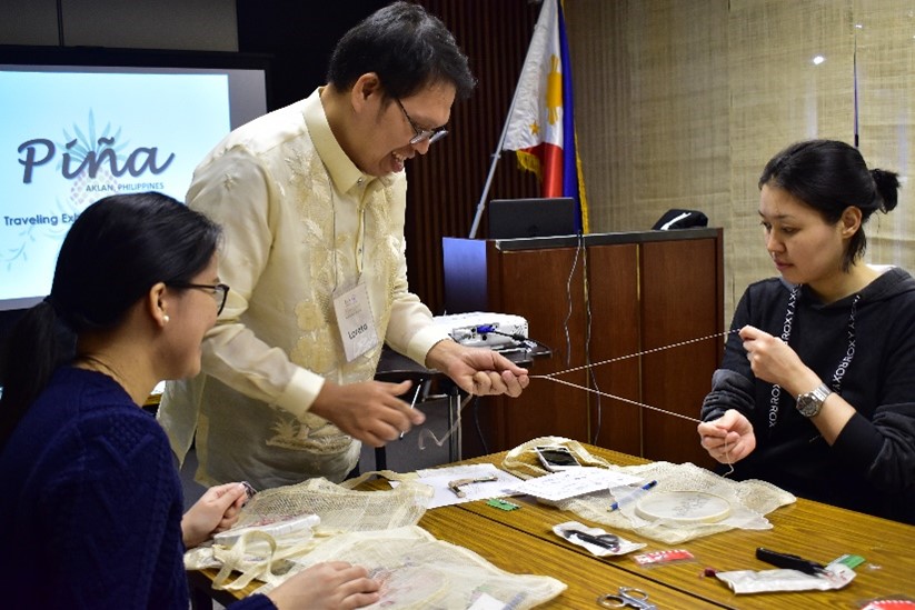 A man showing two women how to embroider