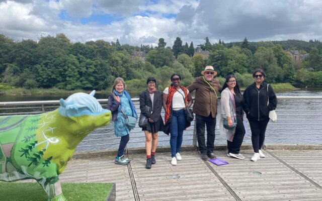 Photograph of 6 people stood by a river.