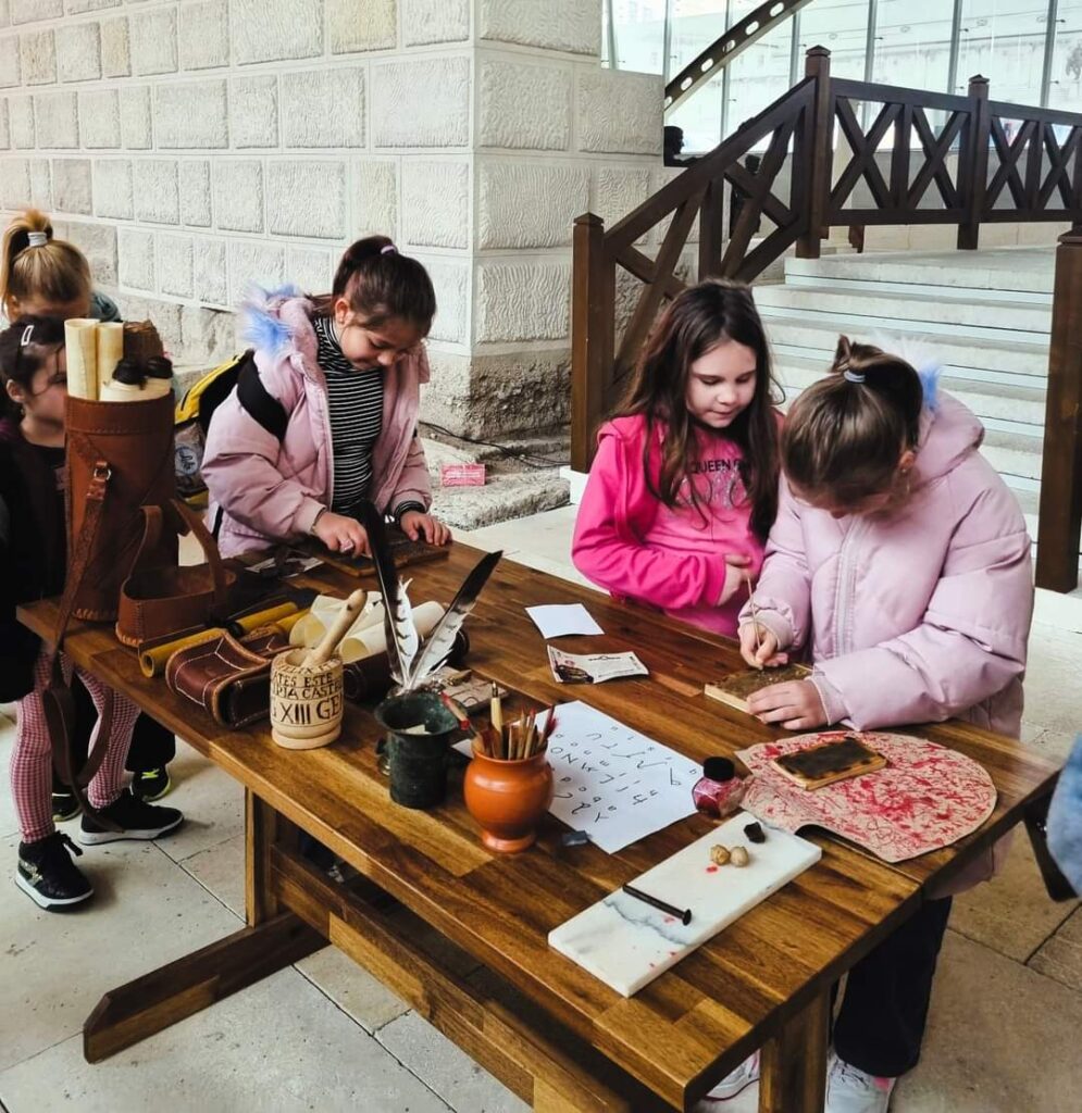 Photograph of children using replica Roman writing materials.