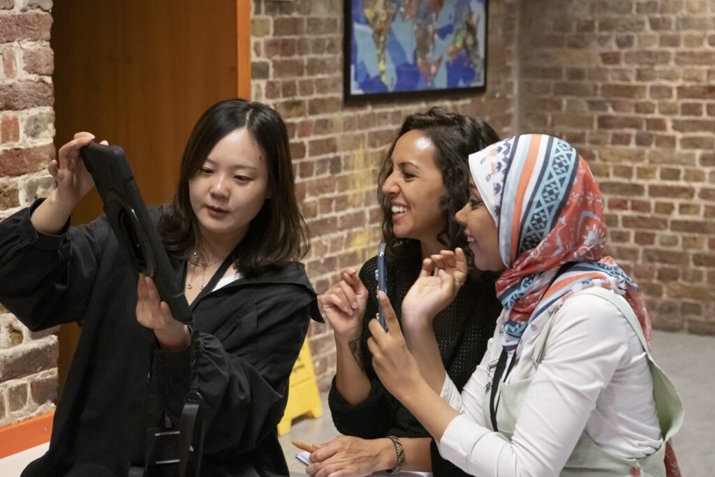 Photograph of three people looking at a tablet device.