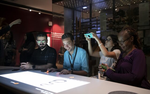 Photograph of four people interacting with a digital display