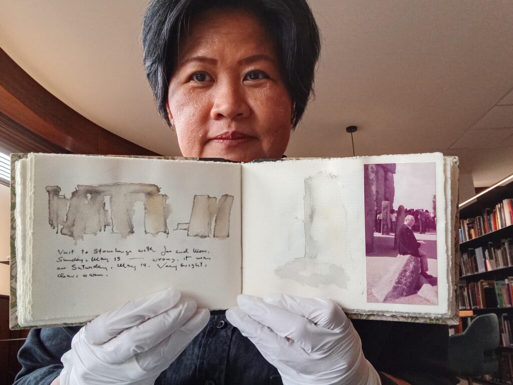 Photograph of a woman holding up a sketchbook.