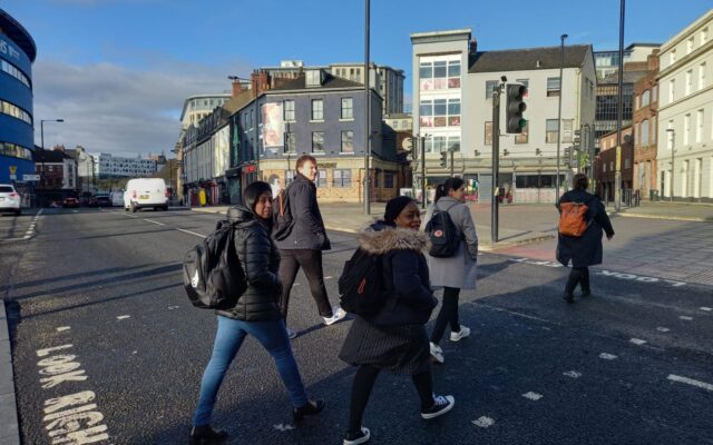 Photograph of five people crossing a road