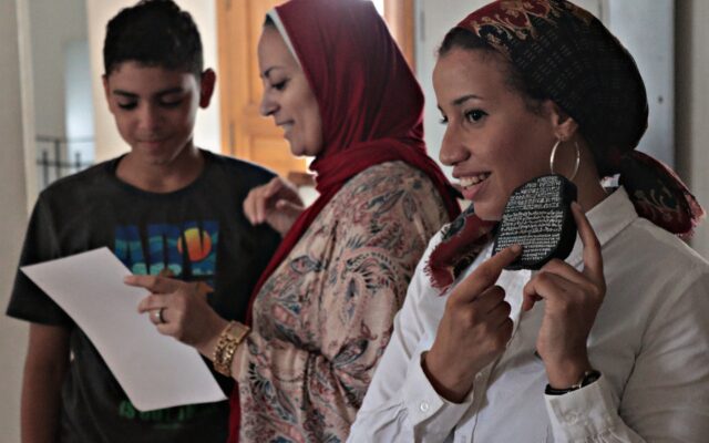 Photograph of a woman holding a mini replica of the Rosetta Stone.