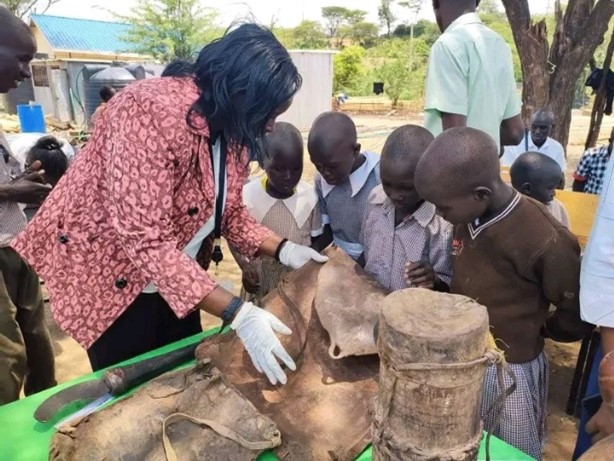 Photograph of children and adults handling objects.