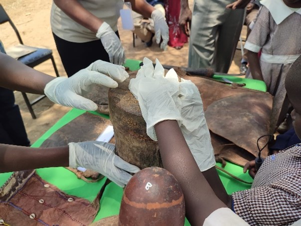 Photograph of children and adults handling objects.