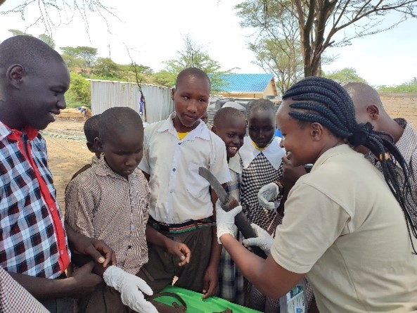 Photograph of children and adults handling objects.