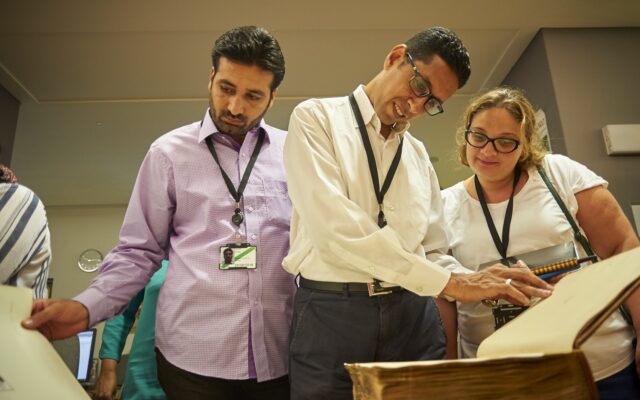 Photograph of three people looking in a book