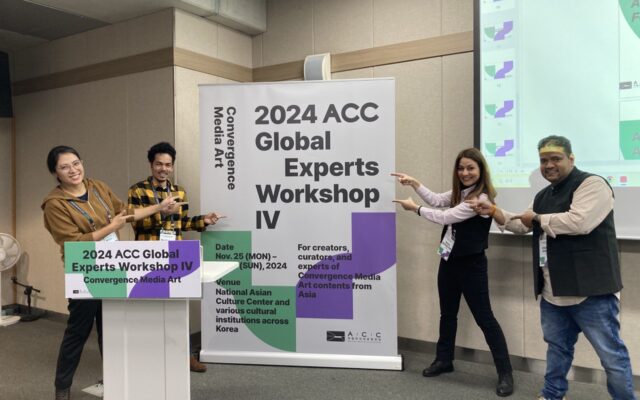 Photograph of four people next to a poster that says '2024 ACC Global Experts Workshop'